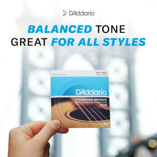 Hand holding D'Addario phosphor bronze guitar strings with blurred background.